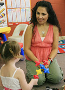 Picture of childcare worker kneeling down to talk with a child.